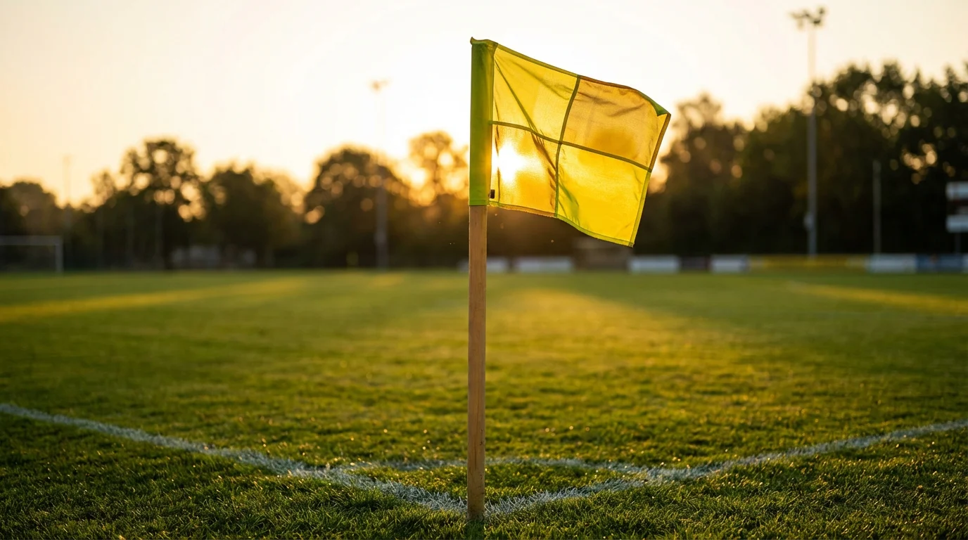 Banderín de córner en la esquina de un campo de fútbol de césped natural al atardecer