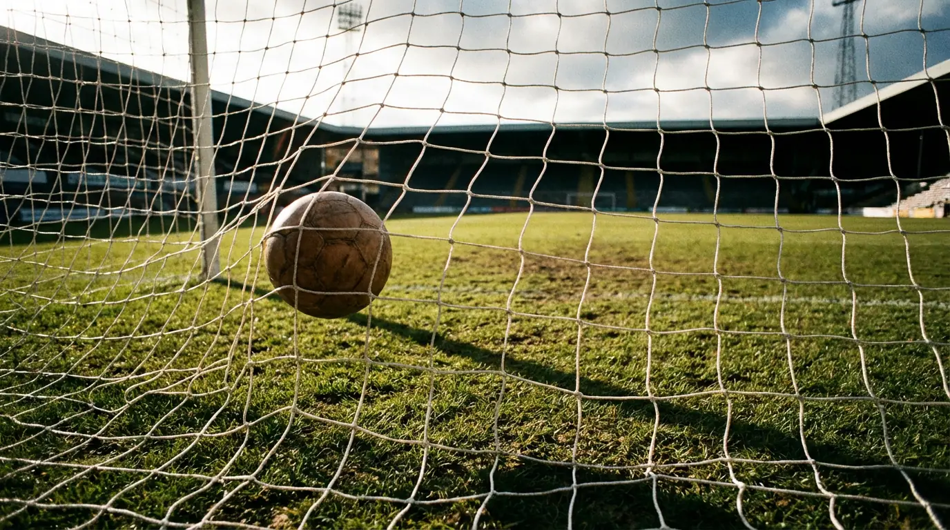 Red de una portería de fútbol vista desde dentro con el balón entrando y el césped del campo al fondo